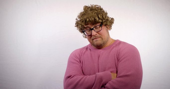crazy man with funny curly wig is looking at camera and taking off it, becoming bald