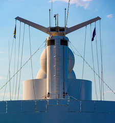 White color satellite antenna of cargo a ship and sun loungers on deck of cruise ship