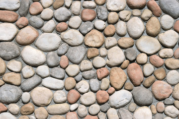 Pebble stone wall texture background. Cement plaster wall decorated by large natural smooth pebble stones. Building facade decoration. 