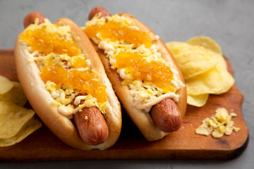 Homemade colombian hot dogs with pineapple sauce, chips and mayo ketchup on a rustic wooden board...