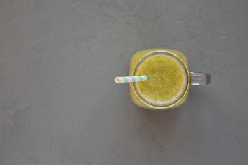 Homemade green cucumber apple smoothie in a glass jar on a gray surface, top view. Flat lay, overhead, from above. Copy space.