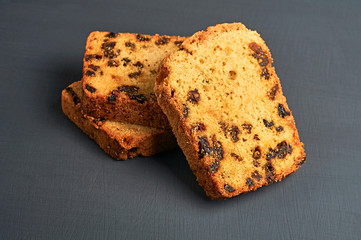Heap of pieces of tasty sweet homemade bread with raisin lies on dark concrete table on kitchen. Close-up