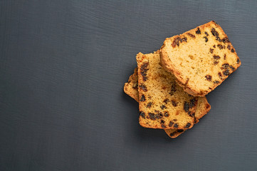 Heap of pieces of tasty sweet homemade bread with raisin lies on dark concrete table on kitchen. Space for text. Flat lay