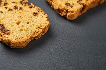 Two scattered pieces of tasty sweet homemade bread with raisin lies on dark concrete table on kitchen. Space for text