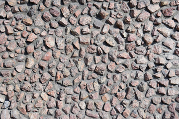 Granite stone wall texture background. Cement plaster wall decorated by unworked stones. Building facade decoration