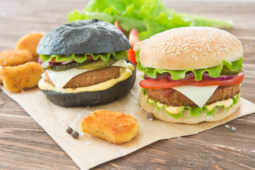 Delicious fast food. Craft beef burgers with vegetables. Flat lay on wooden textured background with sesame seeds.