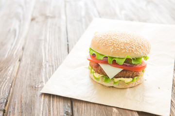Delicious fast food. Homemade hamburger with lettuce, tomato, cheese and cucumber on a cutting board