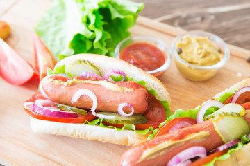 Delicious fast food. Hot dogs with mustard and ketchup on wooden table