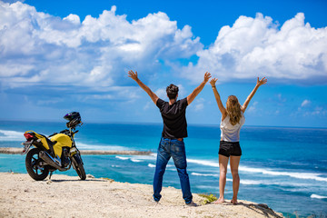 Couple with arms wide open enjoying the ocean / sea view.