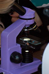 Microscope at a school scientific exhibition. Experiments on chemistry and biology with microscopes. School and student equipment.