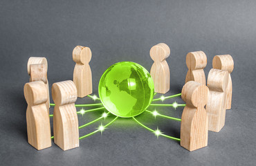 People surrounded a green globe planet earth. Cooperation and collaboration of people around the...