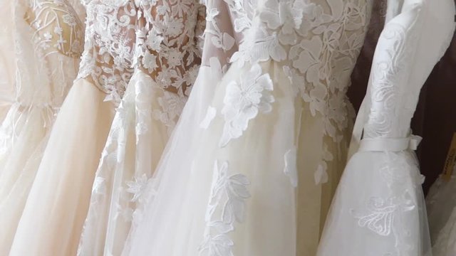 Rack with many beautiful wedding dresses close up.