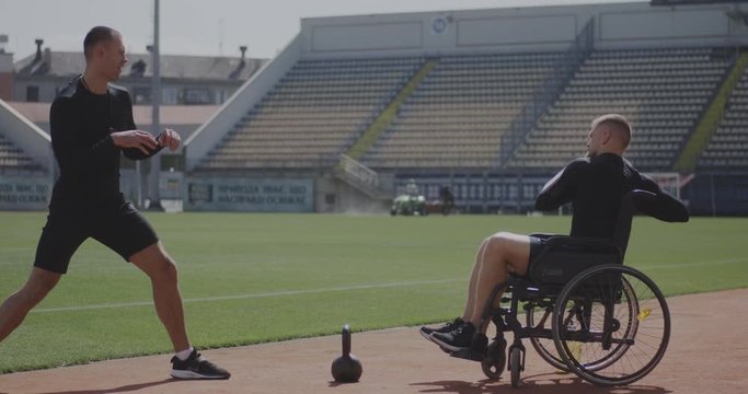 Wheelchaired athlete and trainer throwing medicine ball