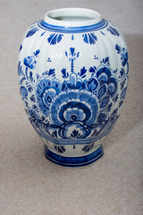 Hand made Dutch Delft Blau (blue) vase with blue designs and porcelin china on an isolated beige background. Netherlands.