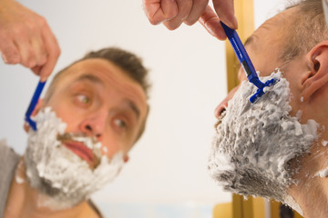 Guy shaving his beard in bathroom