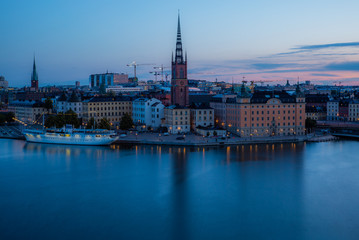 Fototapeta na wymiar A colorful sunrise over Stockholm with the lights reflecting on the calm water of the sea - 5