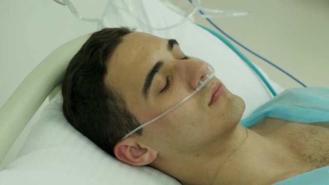 patient lies in intensive care unit unconscious 