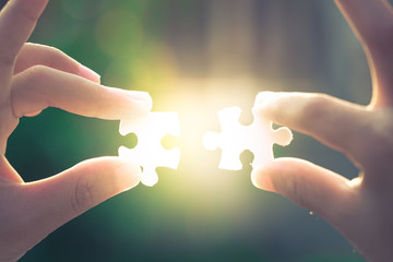Two hands holding a jigsaw puzzle on the evening light
