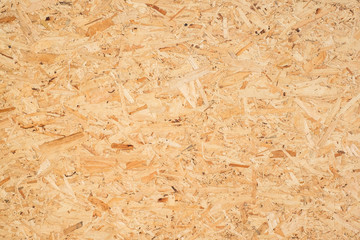 OSB boards are made of brown wood chips sanded into a wooden background. Top view of OSB wood veneer background, tight, seamless surfaces.