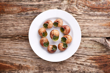 Escargots de Bourgogne - Snails with herbs butter on wooden background. Salad. Parsley.