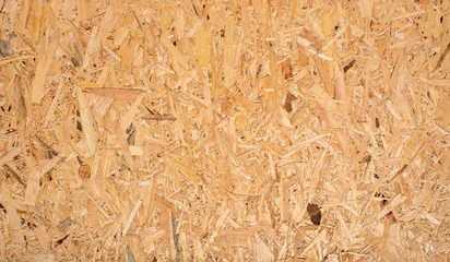 OSB boards are made of brown wood chips sanded into a wooden background. Top view of OSB wood veneer background, tight, seamless surfaces.