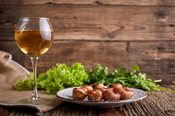 Escargots de Bourgogne - Snails with herbs butter on wooden background. Salad. Parsley. Glass of wine.