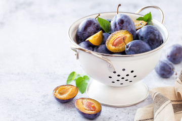 Fresh ripe plums in a colander with copy space for your text
