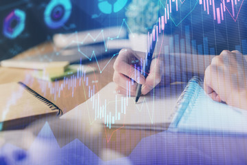 Financial forex graph drawn over hands taking notes background. Concept of research. Multi exposure