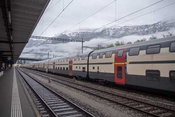 Fototapeta na wymiar Train stops in empty station on foggy mountain background with copy space