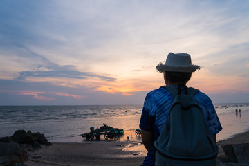 tourist with backpack of freedom on sand beach in silhouette of asian young woman relaxing, standing looking sunset scene in summer sky outdoor. journey trip outdoors in summer concept