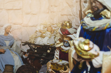 Christmas Nativity scene with The Holy Child, The Blessed Virgin Mary, Saint Joseph, ox and donkey in evening. Selective focus, noise effect