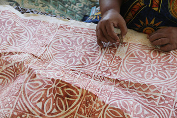 A Samoan lady drawing traditional pattern with mud water on a handmade mulberry paper.