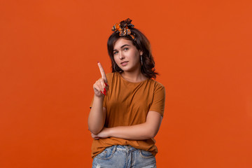 Pretty brunette woman in a t-shirt and beautiful headband wagging a finger standing isolated over...