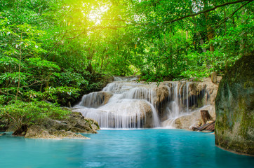 Fototapeta na wymiar Deep forest waterfall at Erawan waterfall, beautiful waterfall with sunlight rays in deep forest, Erawan National Park in Kanchanaburi, Thailand