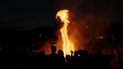 people stand around a big bonfire at a festival