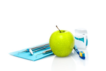 Set of dentist medical equipment tools with fresh green apple dental health care conceptual background image.