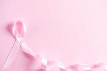 Pink ribbon on pink pastel paper background for supporting breast cancer awareness month campaign.