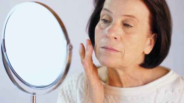Elderly woman looking at skin on the face