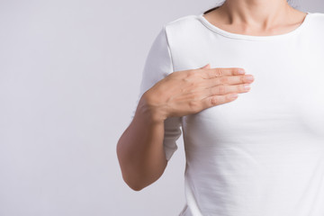 Woman hand checking lumps on her breast for signs of breast cancer on gray background. Healthcare...