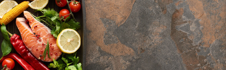 top view of raw salmon with vegetables, lemon and herbs in grill pan, panoramic shot