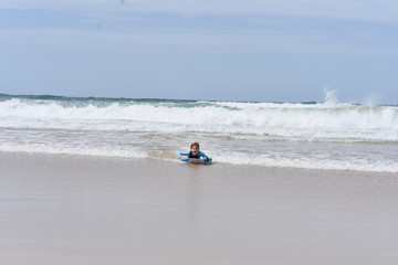 Fototapeta na wymiar child on a boogie board surfing a wave at the beach at the Gold Coast Australia