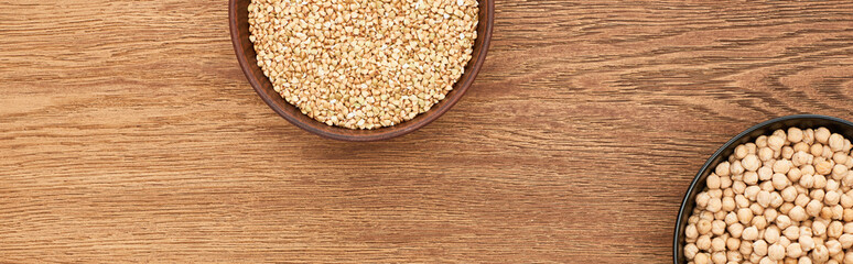 bowls with raw buckwheat and chickpea on wooden surface with copy space