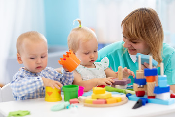 Obraz na płótnie Canvas Nursery teacher and cute babies playing in creche