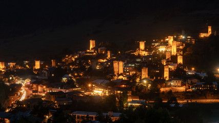 Fototapeta na wymiar Night view on Mestia with its beautiful illuminated Svan Towers and high mountains. Svaneti, Georgia.