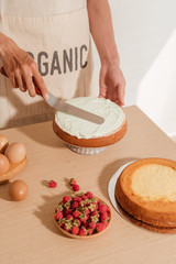Man pastry chef put icing cream on sponge cake. Making sponge cake series
