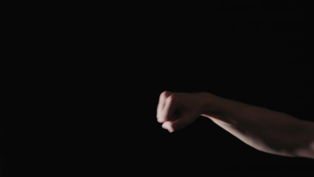 Slow motion man fist punch on black background