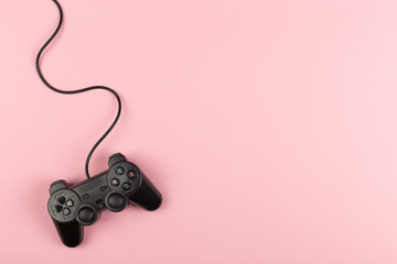 Gamepad with a cord on a pink background, weekend concept, gaming hobby. Copy space.