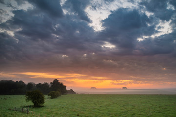 Stunning inspirational Summer sunrise landscape image over English countryside with mist hanging in fields