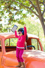 Little girl listening to music on the tablet with her headphones in the truck car