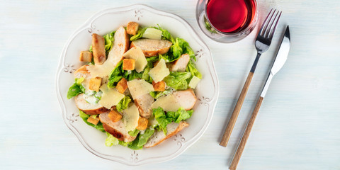 A panorama of a chicken Caesar salad with rose wine, shot from the top with a place for text